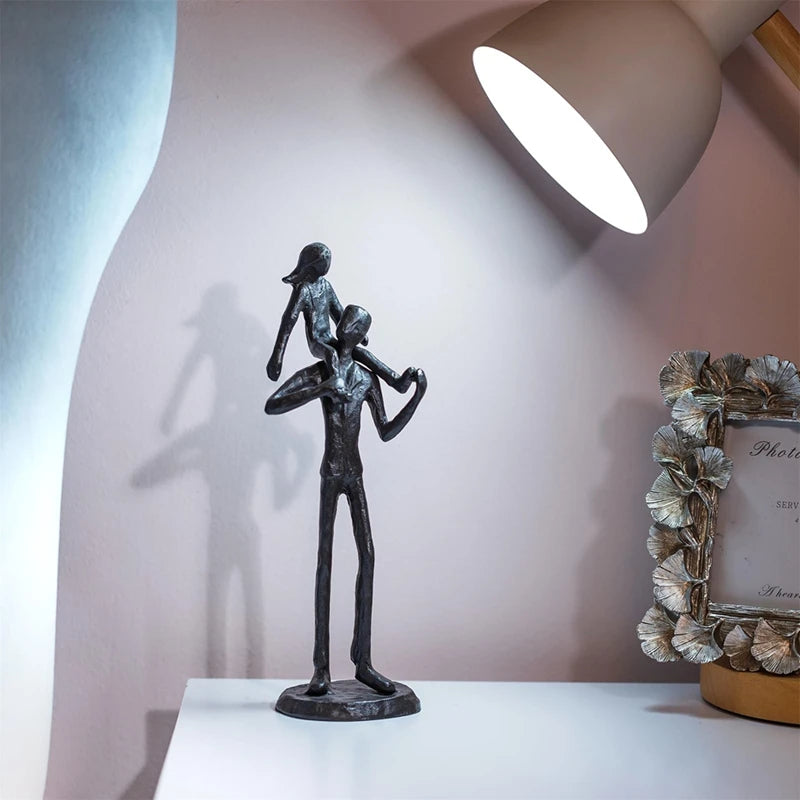 Iron figurine of man carrying child on shoulders on table.