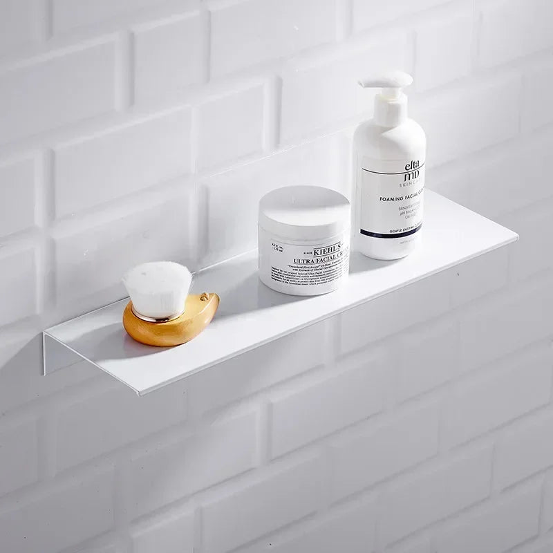 White floating wall shelf with soap dispenser and decor against tiled wall.