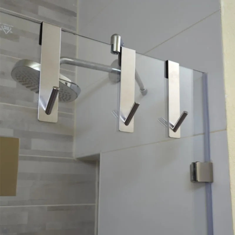 Modern towel rack with multiple hooks installed on a glass shower door.