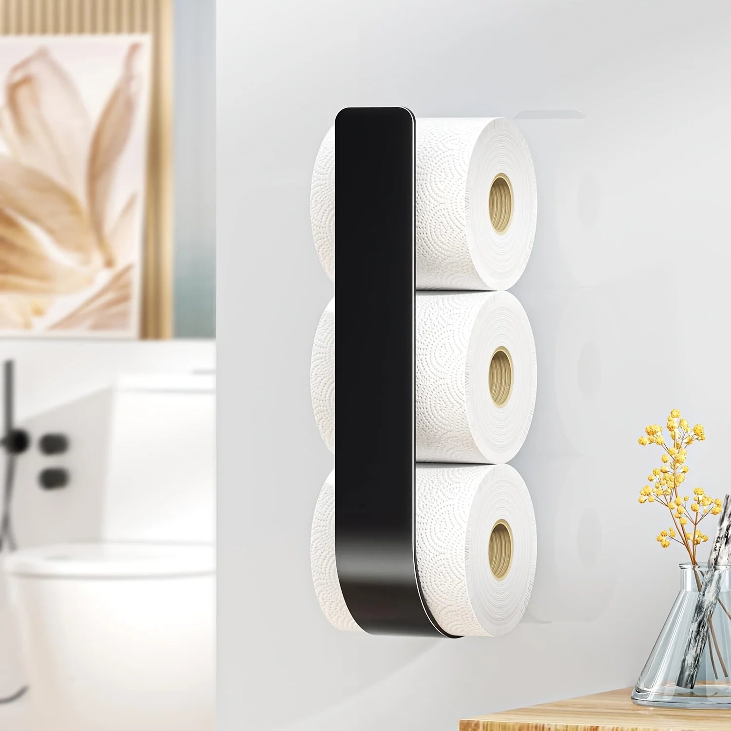 A black wall-mounted toilet paper rack holding three rolls vertically, in a bathroom setting.