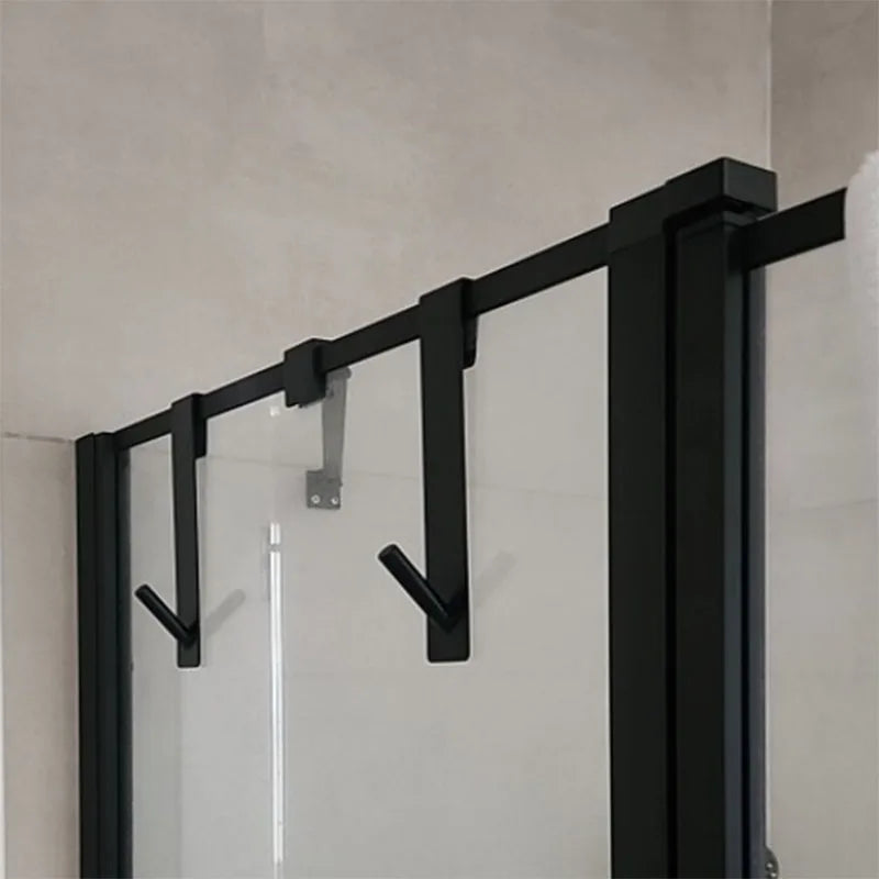 Over-the-door black towel rack with multiple hooks holding brushes and accessories.