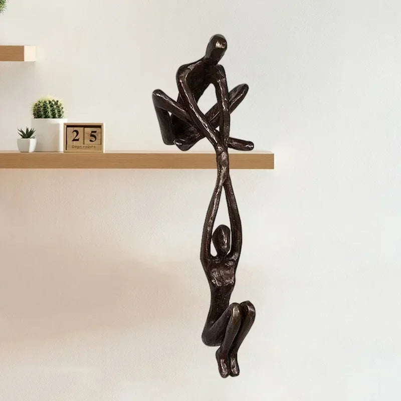 Bronze climbing sculpture ornament of two figures hanging from a shelf.