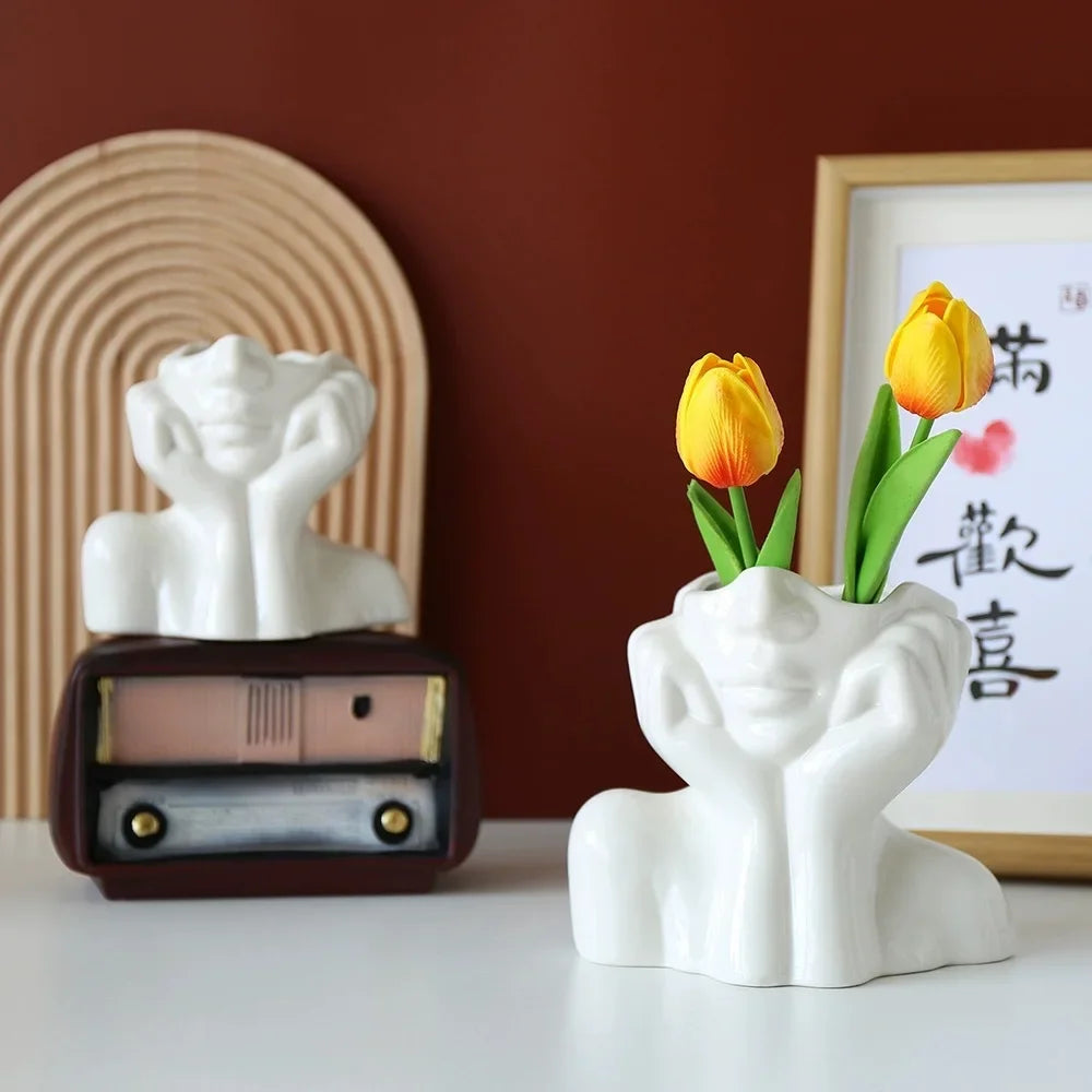 White body shape vase holding tulips and books in the background.