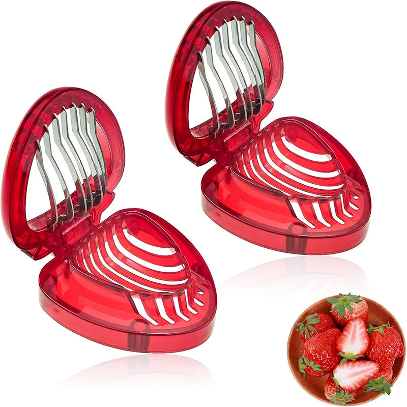 Two red, heart-shaped strawberry slicers, one open with a small bowl of sliced strawberries.