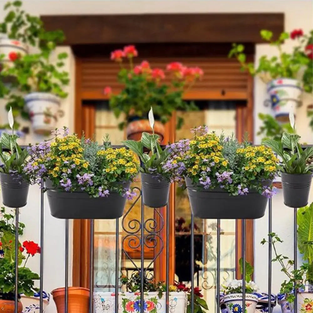 Row of hanging flower pots with mixed flowers on a metal railing.