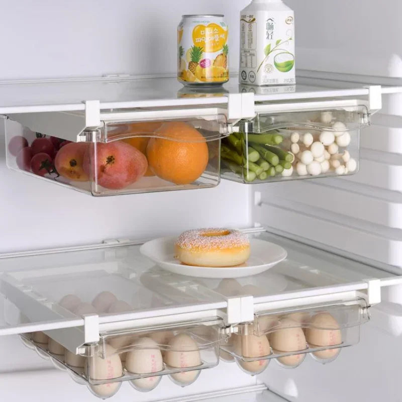 Clear refrigerator drawers holding fruits, mushrooms, and eggs with an open shelf space.