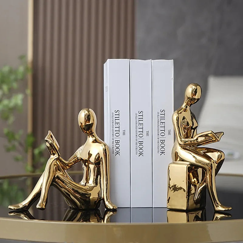 Gold bookshelf stopper set placed on a table supporting books.