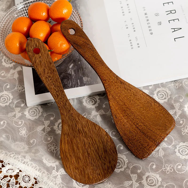 Two pieces of wooden kitchenware displayed next to decorative fruits.