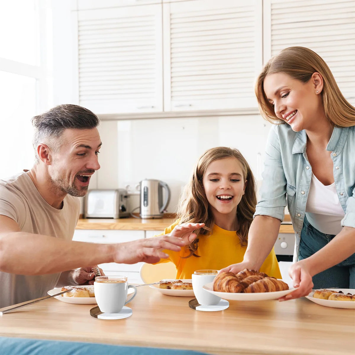 Happy family at a kitchen table enjoying breakfast with drinks and coffee coasters.