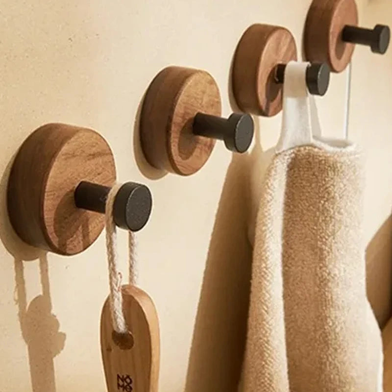 Four round wood hooks with black pegs, holding a towel and a brush.