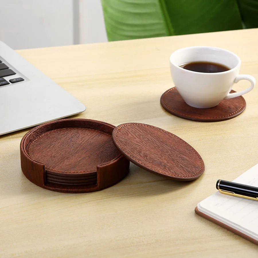 Brown wood-grain leather coasters with holder, one coaster out with a white cup.