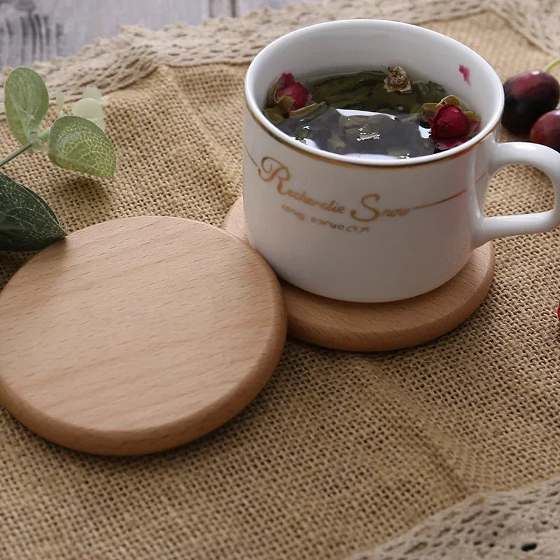 A round light wooden coaster under a white ceramic tea cup on a burlap cloth