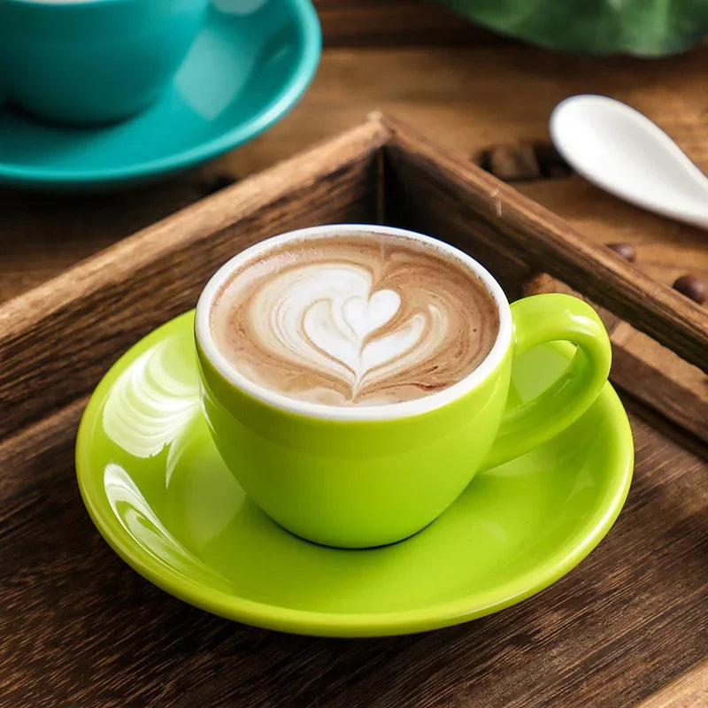 Green ceramic mug with heart latte art on a saucer.
