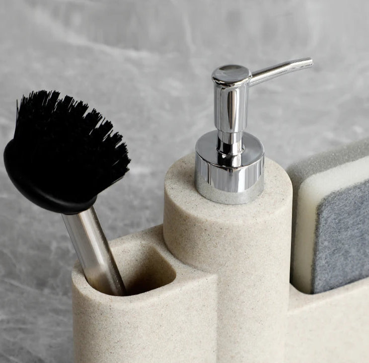 Beige dish soap dispenser with chrome pump, brush, and sponge in holder.