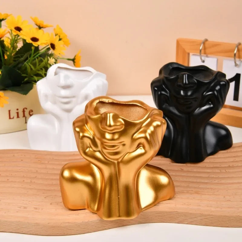 White and black body shape vase set placed on an orange tabletop.