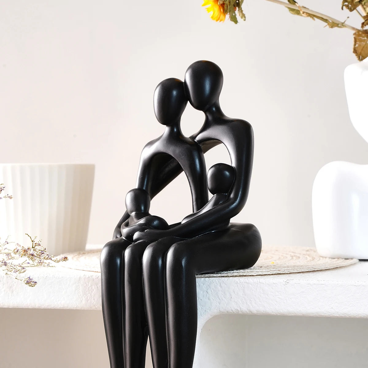 Black desk statue of a couple sitting and embracing with minimalistic design.