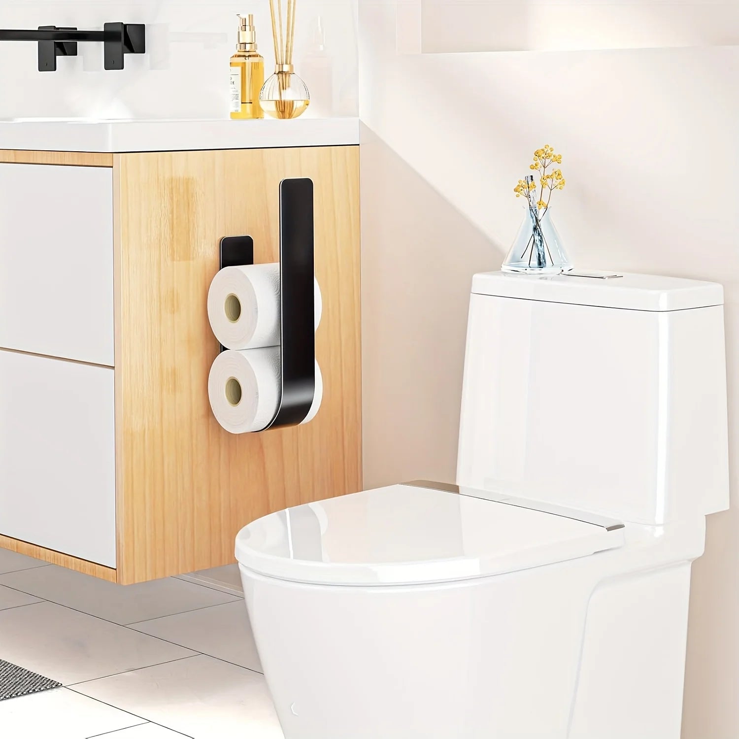 A black wall-mounted toilet paper rack holding two rolls next to a white toilet.