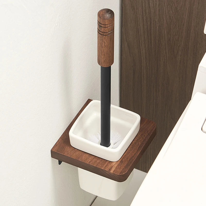 A wall-mounted wooden toilet brush holder with a white ceramic insert and a toilet brush inside