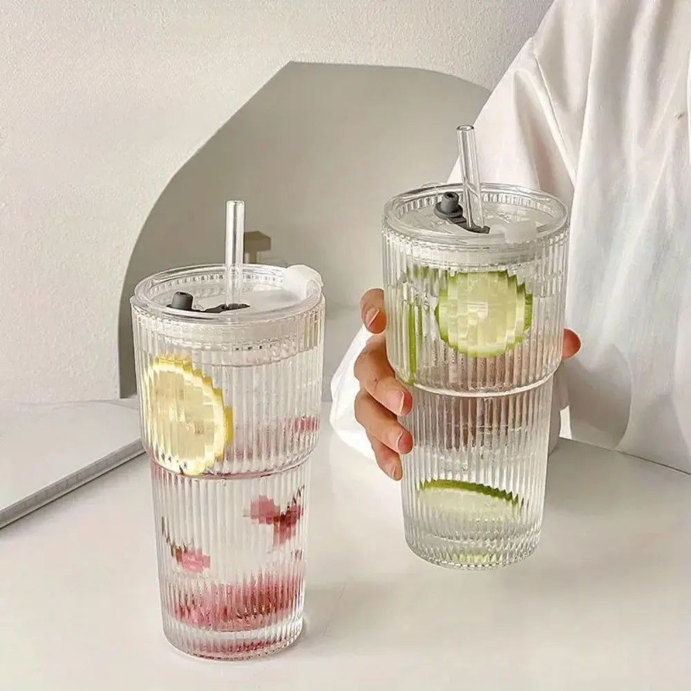 Glass cup with lid and straw, filled with lemon and cucumber water.