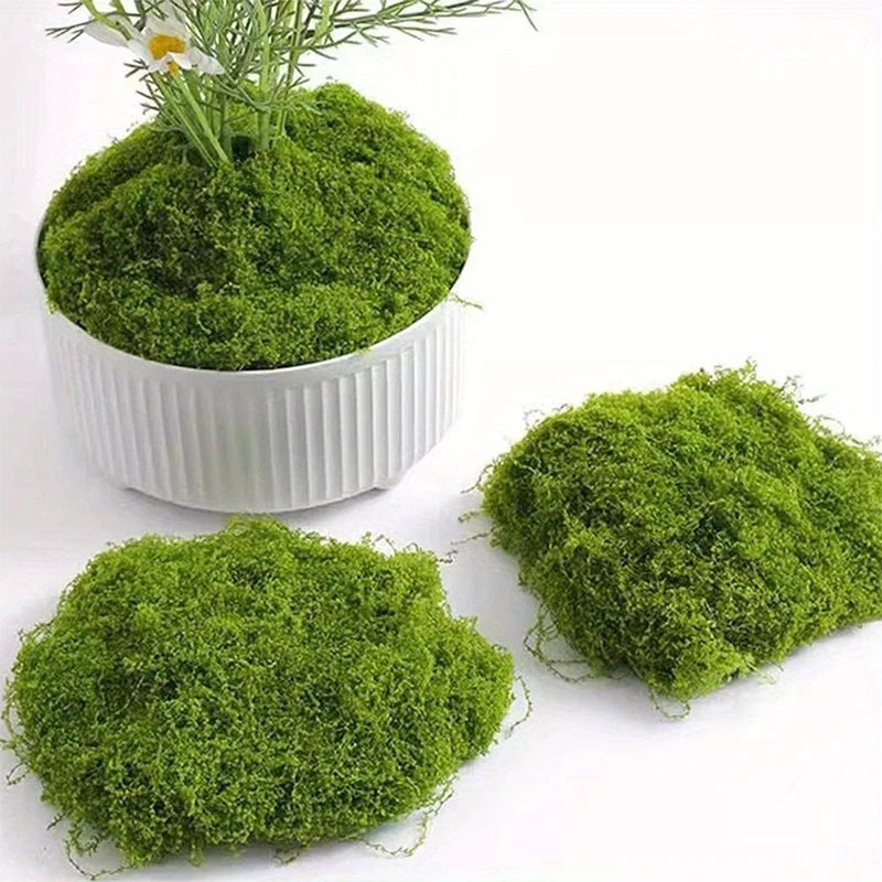 Close-up of fake moss arranged around a wine glass and planters.