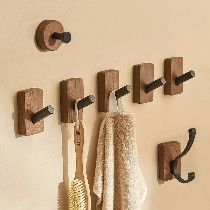 Several wood hooks of different styles on a wall, some holding items.