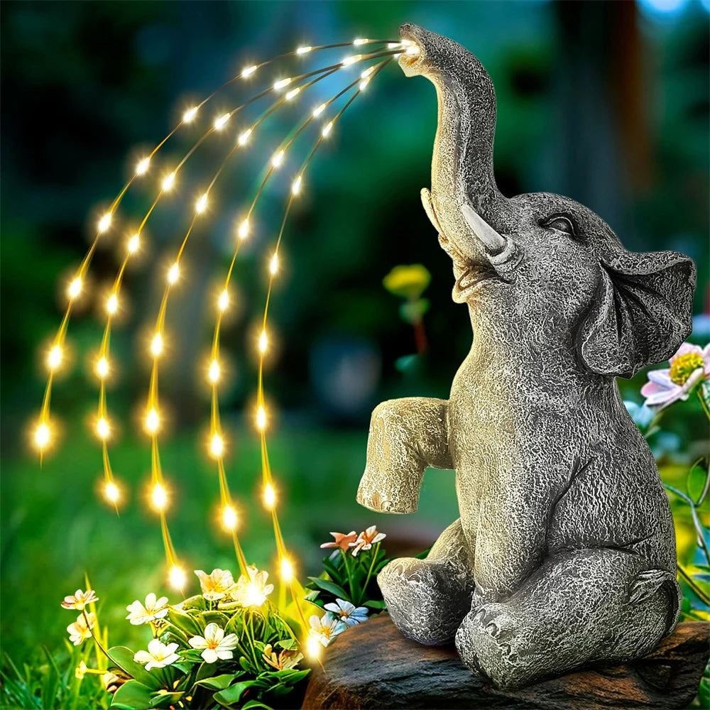 Elephant statues spraying string lights in a garden at night.