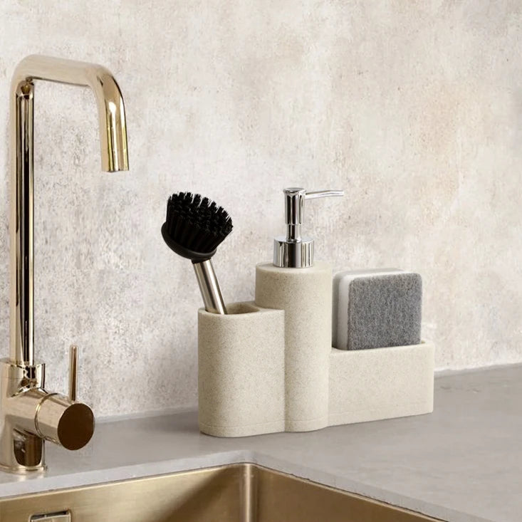 Beige dish soap dispenser with sponge and brush on countertop.