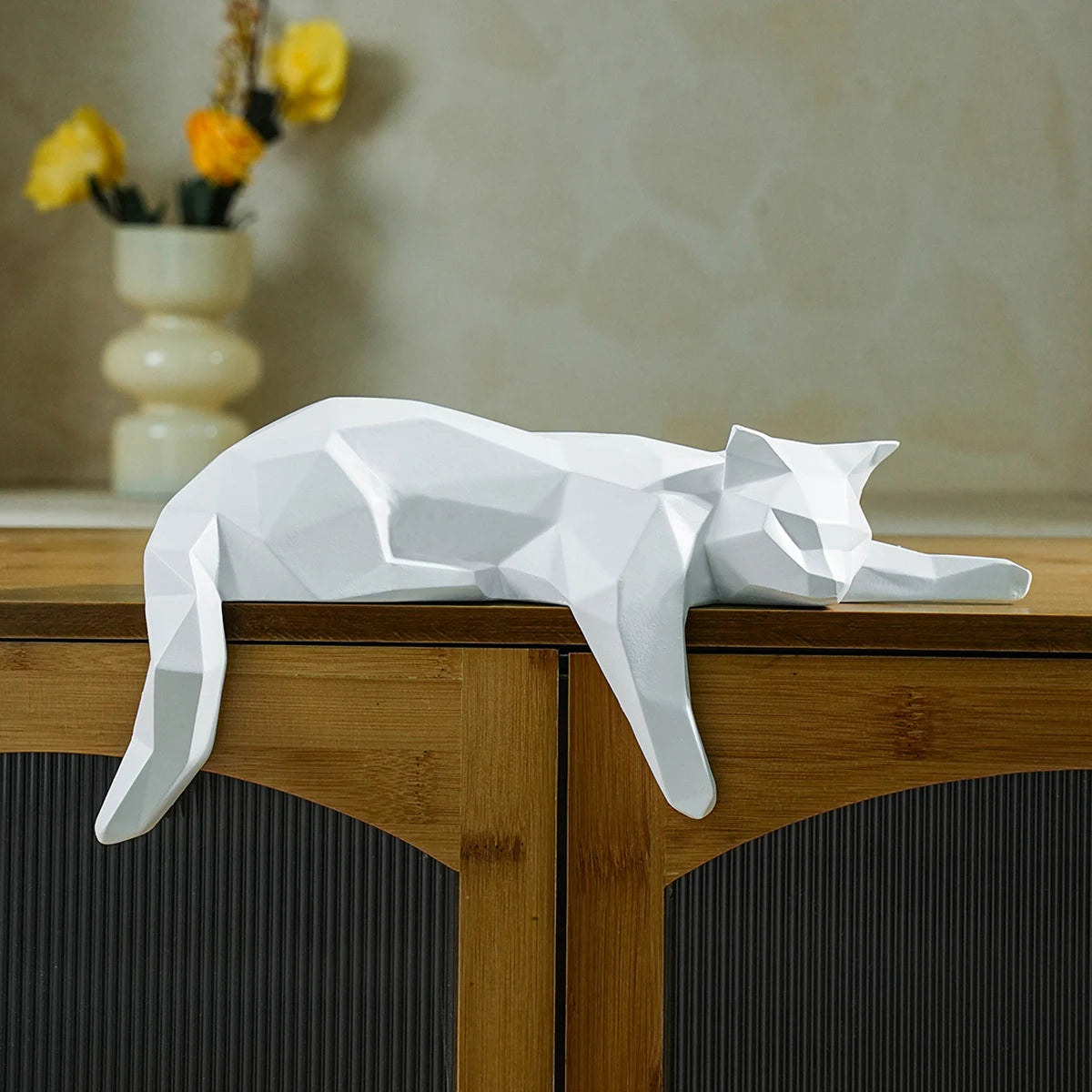 White cat geometric decor lying on the edge of a wooden cabinet.