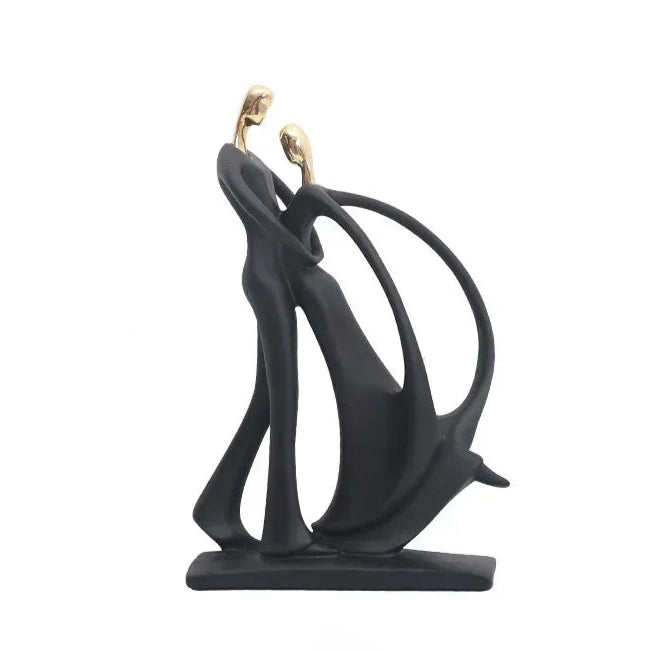 A golden dancing figurine of two abstract figures on a black stand