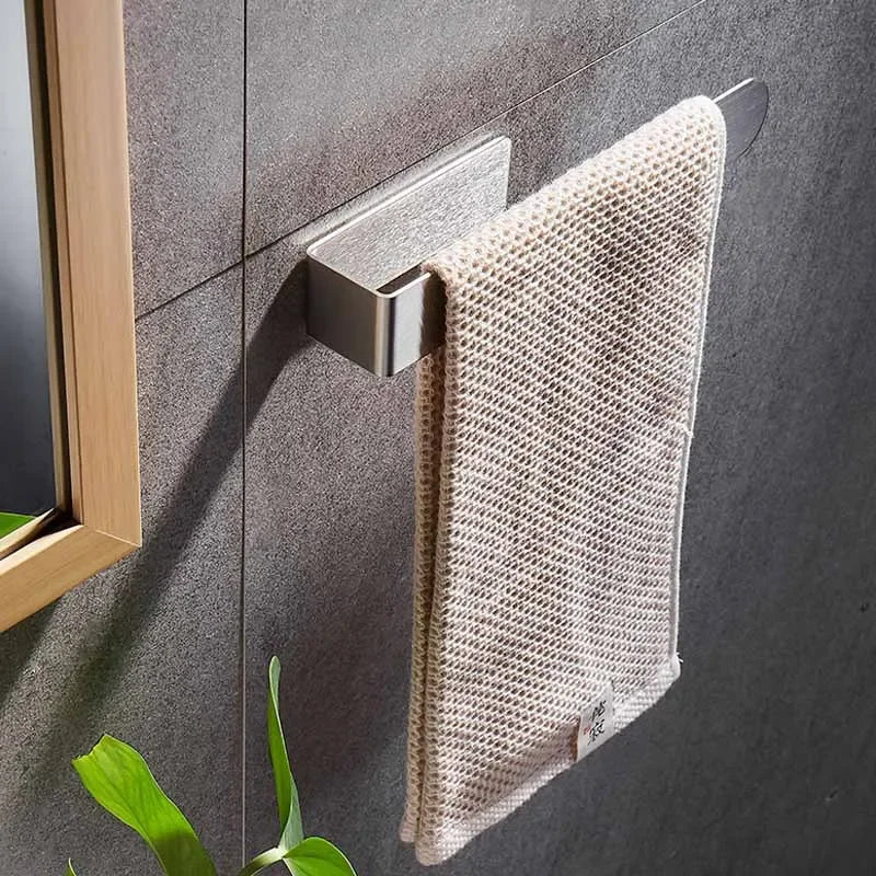 Silver adhesive towel ring with beige towel on gray wall.