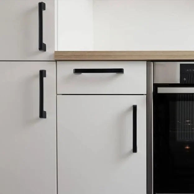 White kitchen cabinets with black kitchen cabinet knobs in a modern kitchen setup.