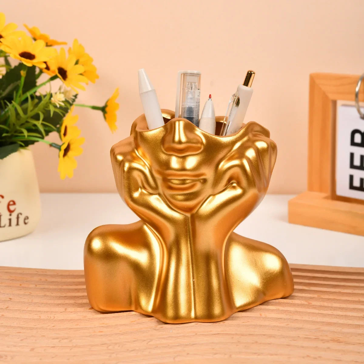 Gold body shape vase used as a pen or brush holder on a desk.