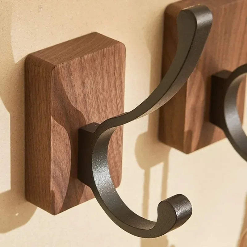 Two rectangular wood hooks with dark, curved metal arms.