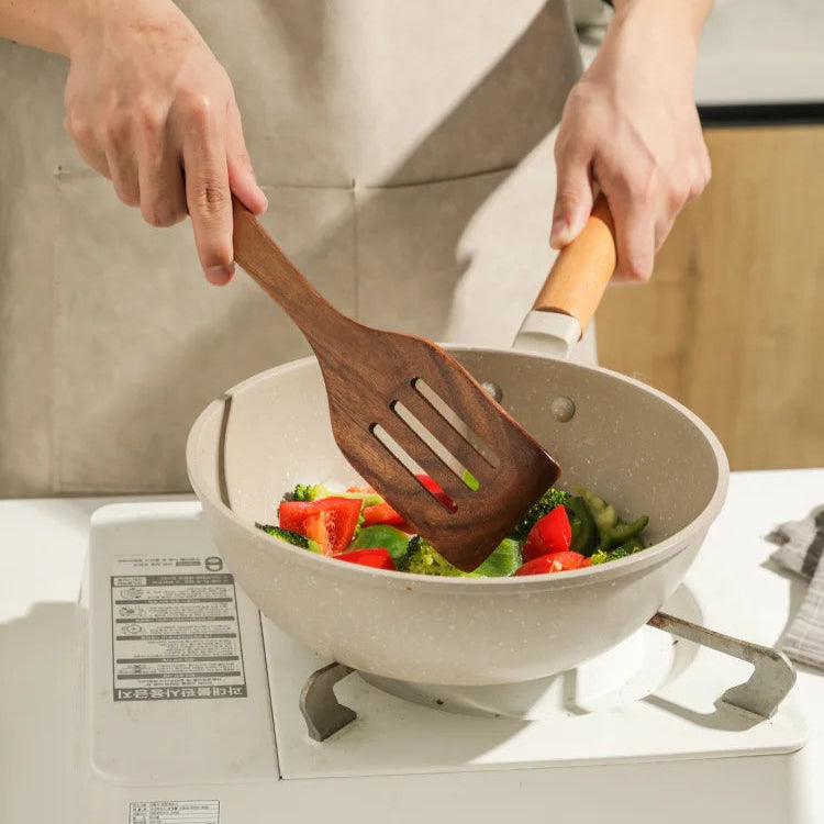 Stirring food in a pot using wooden kitchenware set.