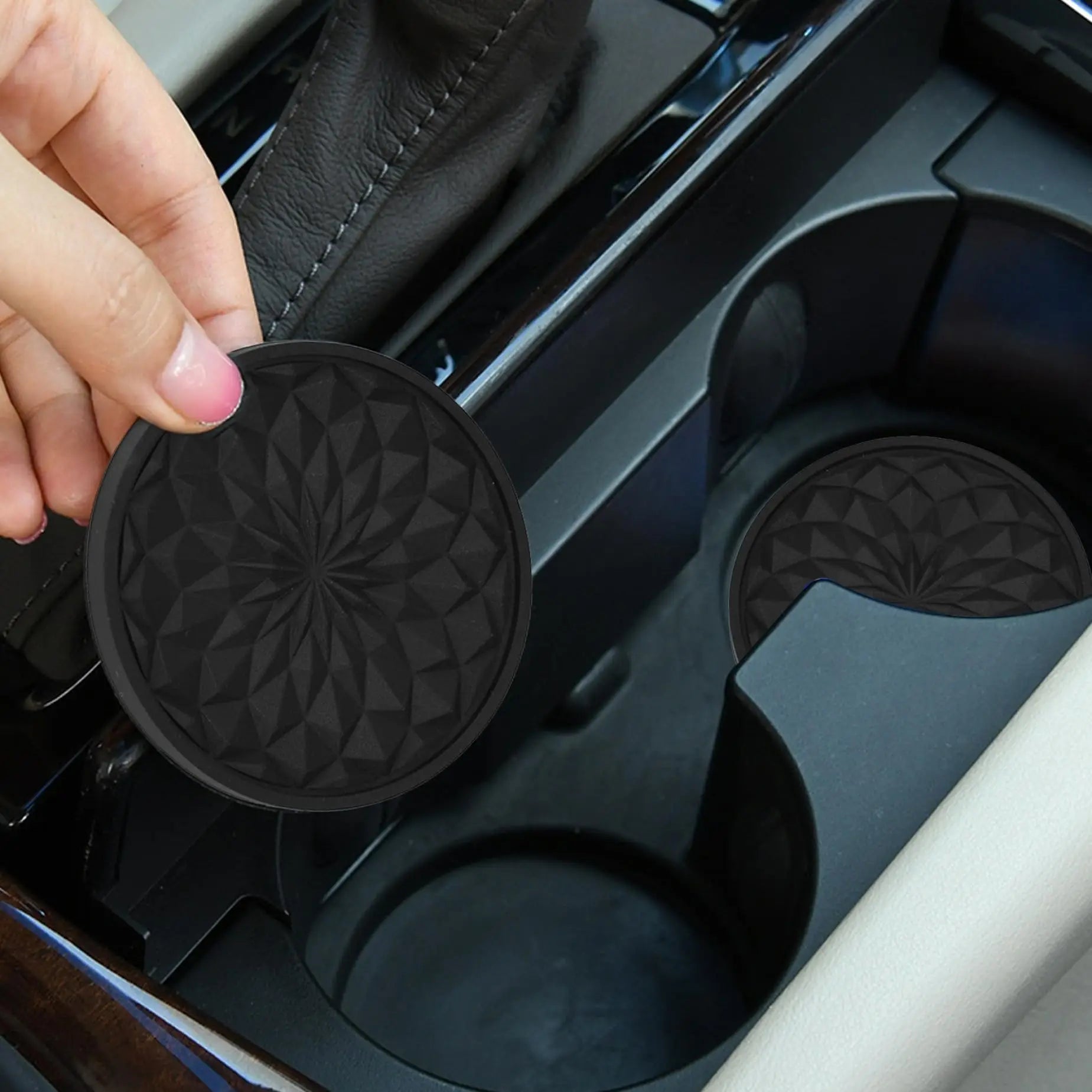 A silver bottle in a car's cup holder, which contains a black, textured coaster.