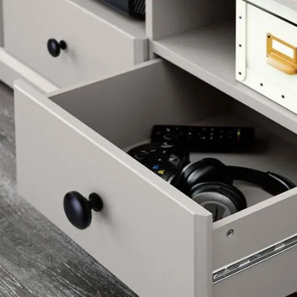 Open drawer with kitchen cabinet knobs showing contents like headphones and remote.