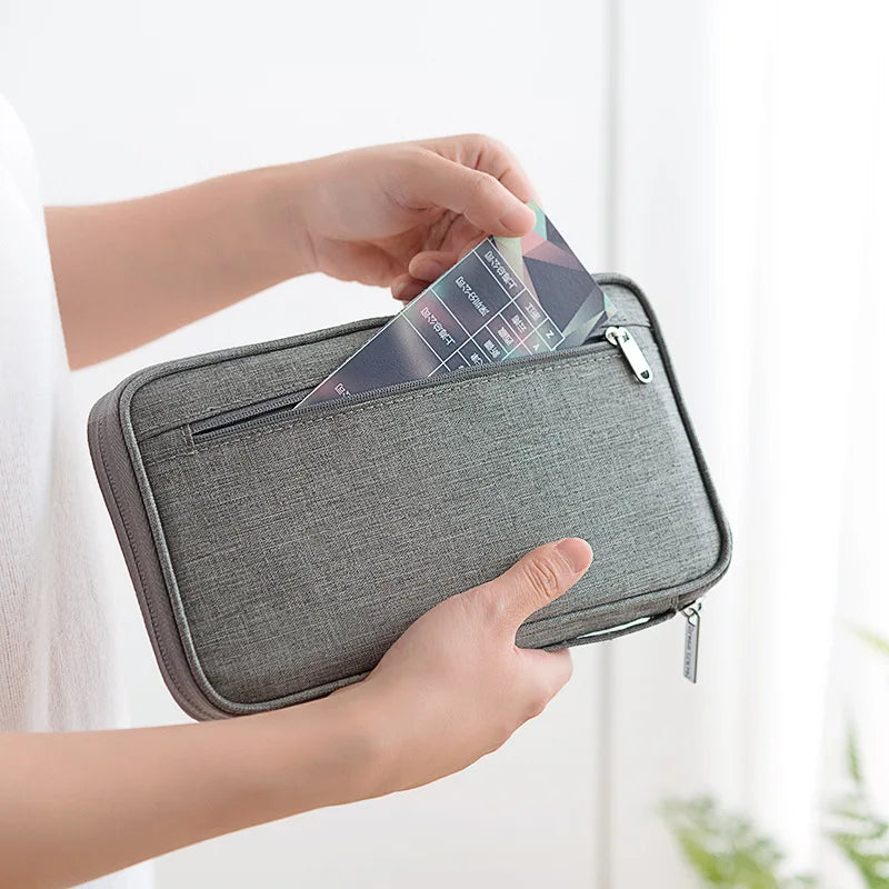 Hand putting document into grey travel wallet's front pocket.